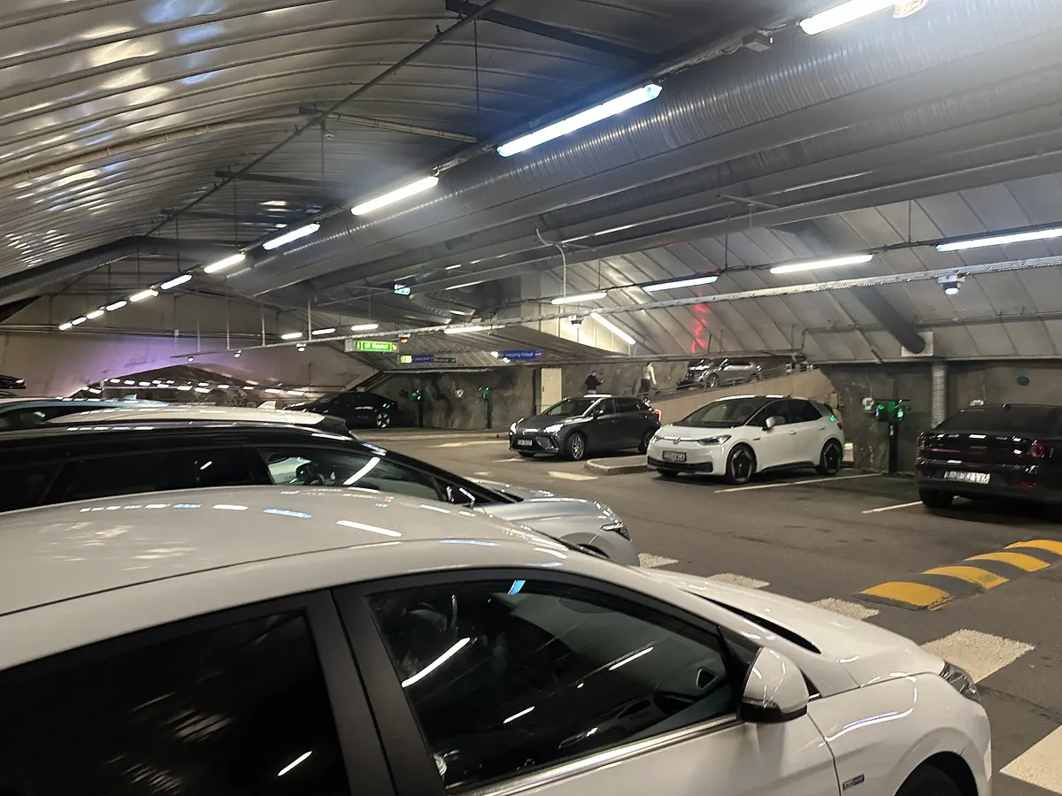 Parked cars on level E of KlosterGarasjen, with charging points along the wall