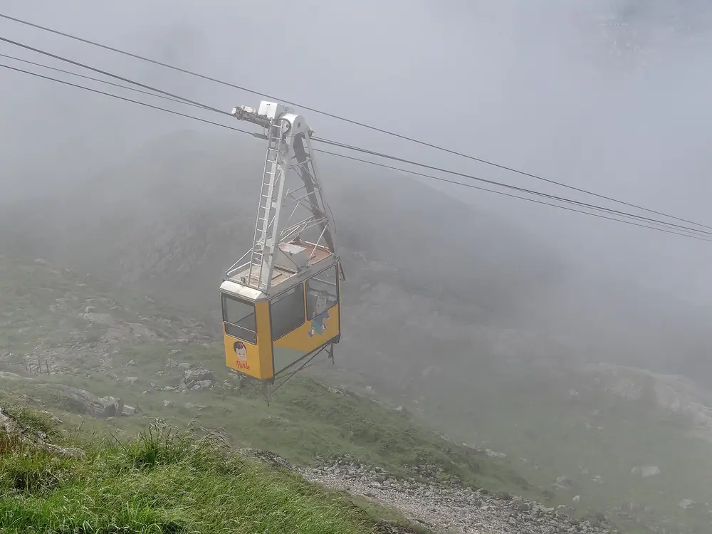 The yellow Ulriken cable car car climbing the mountainside through thick fog