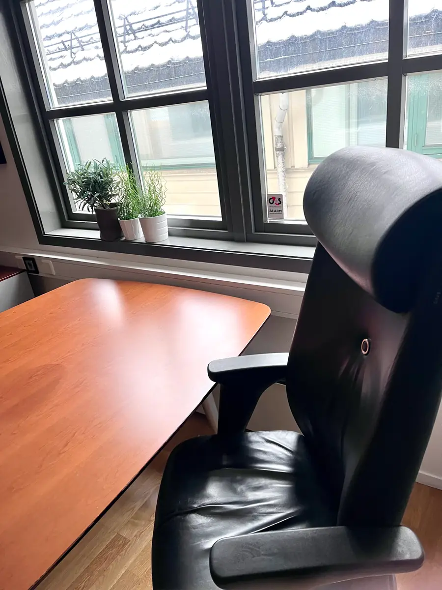 Skrivebord og kontorstol ved vindu med utsikt til nabobygget